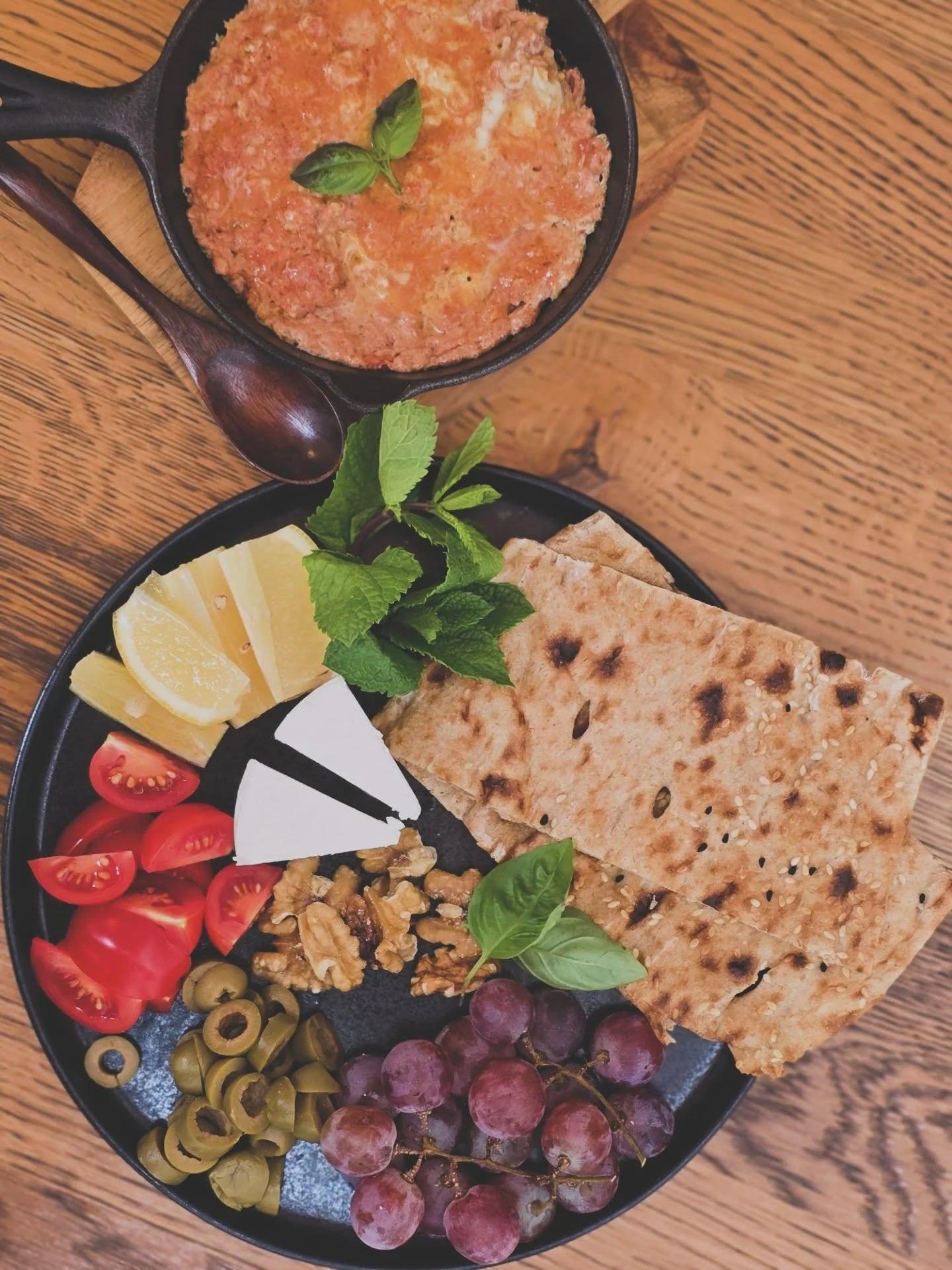 Persisches Omelette in der Gusseisenpfanne mit Fladenbrot, Weißkäse, Walnüssen, Trauben und Minze
